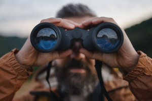 man peering through binoculars
